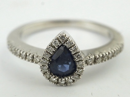 A modern 18k and single stone pear cut sapphire set ring, with diamond chip set border and shoulders, size L, gross weight 3 grams. Condition - good